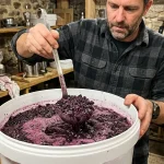 Winemaker punching down fruit cap in fermentation vessel